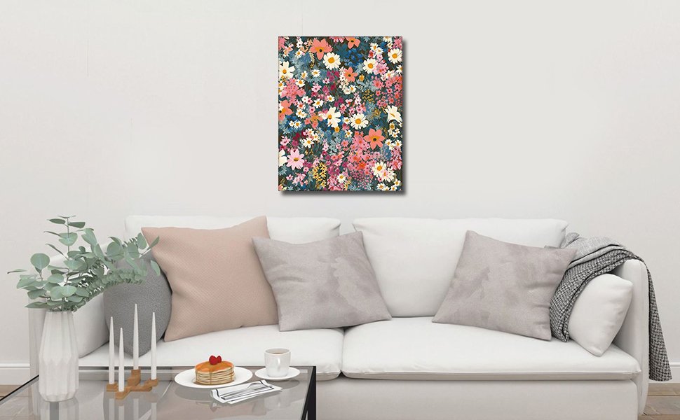 Frameless floral acrylic paint by number kit artwork hanging above a white sofa with decorative pillows and a throw blanket.