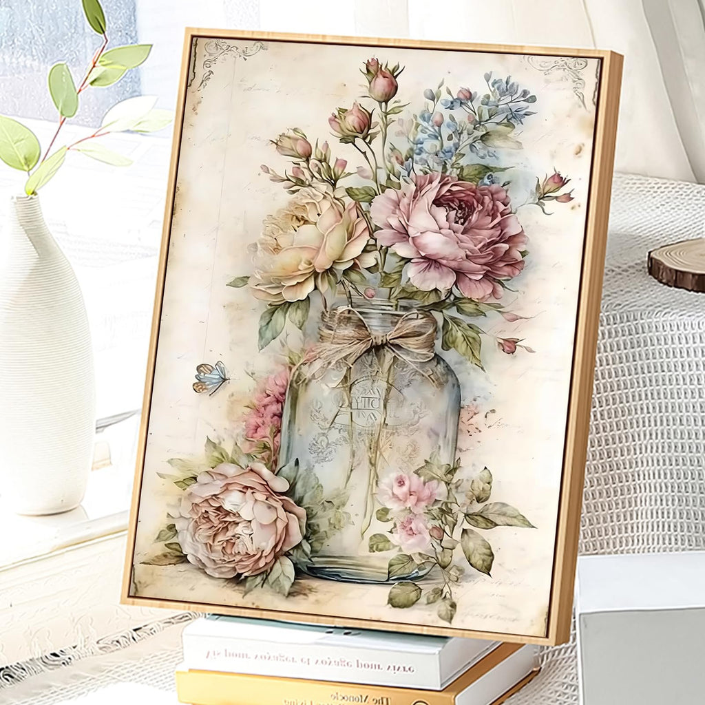Framed floral painting of roses in a glass jar with a butterfly, displayed on books by a window.