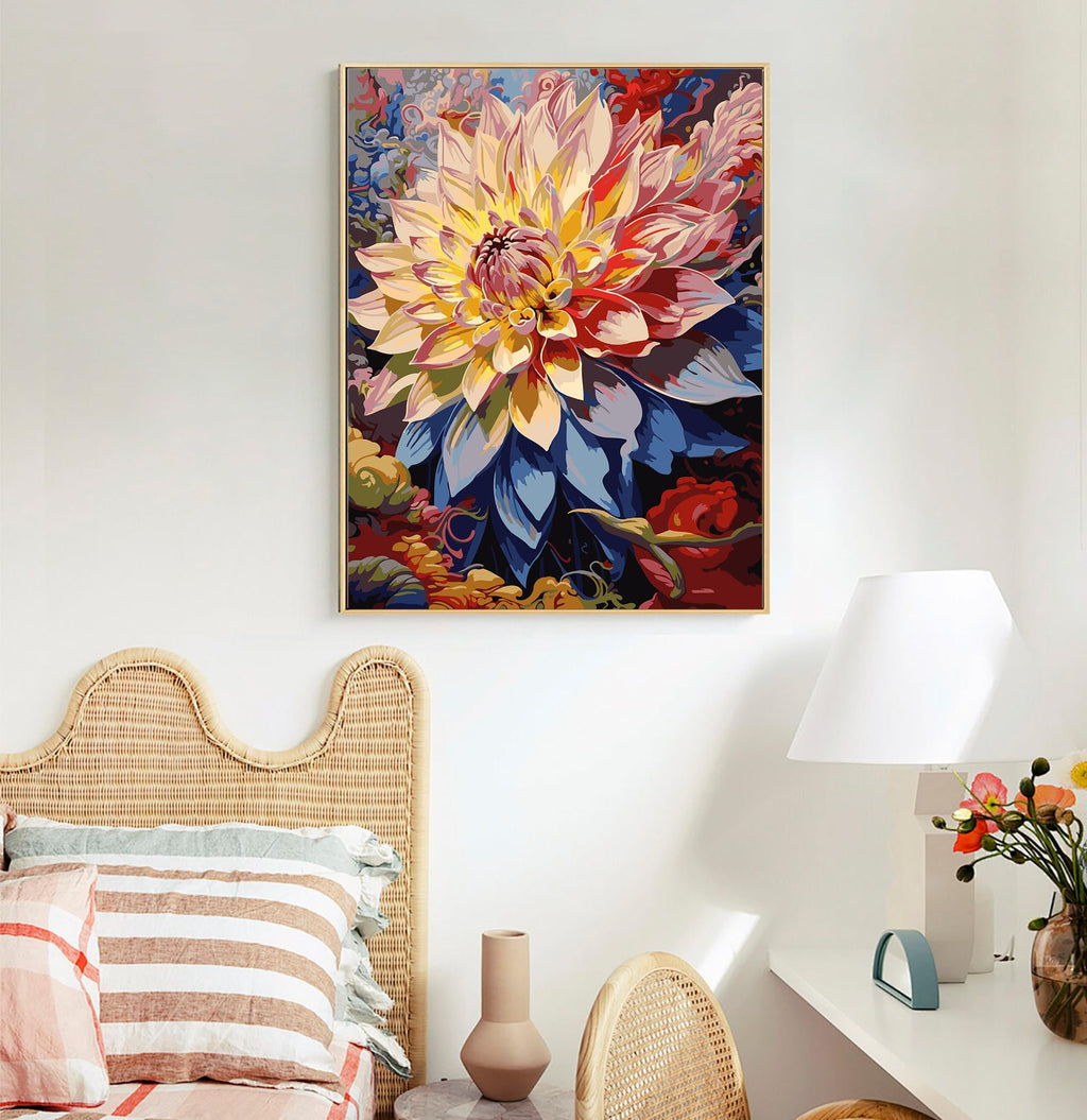 Framed paint by numbers artwork of a vibrant dahlia flower hanging above a bed and desk.