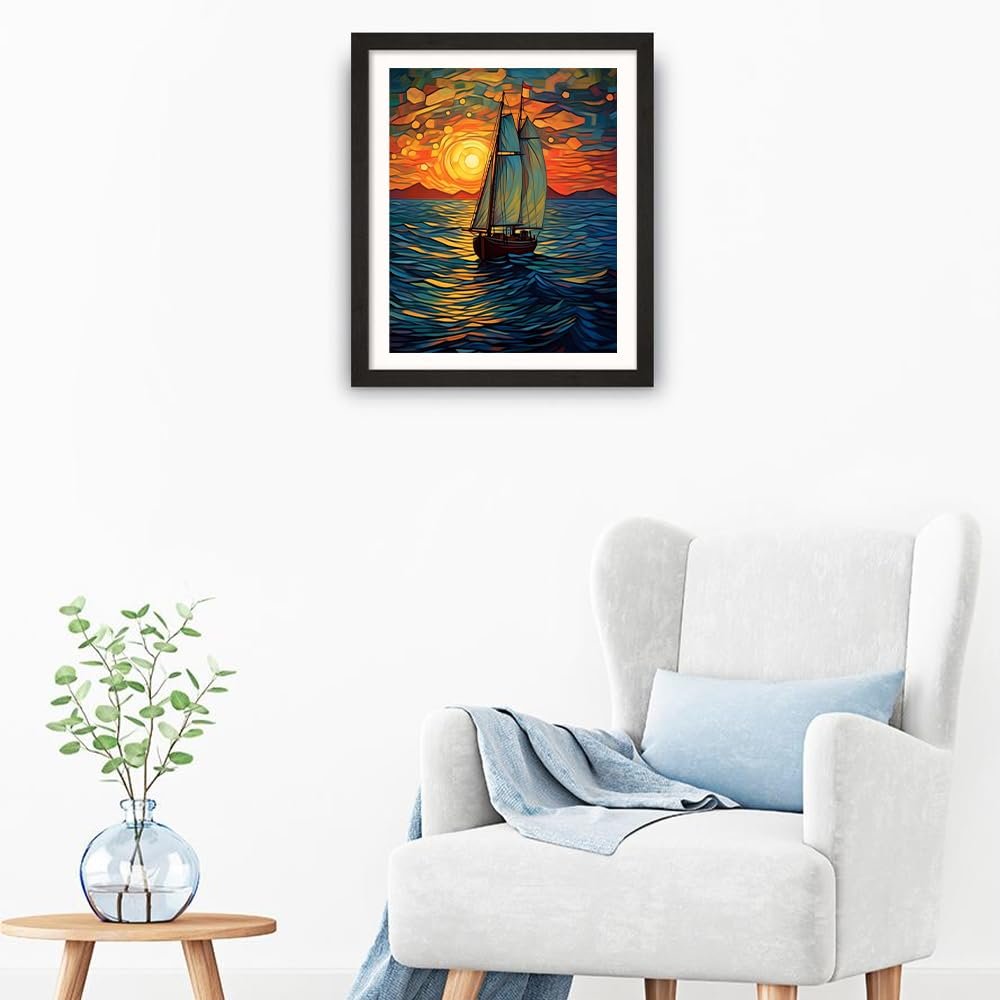 Framed sailboat painting on a wall above a chair, depicting a sunset over the ocean.