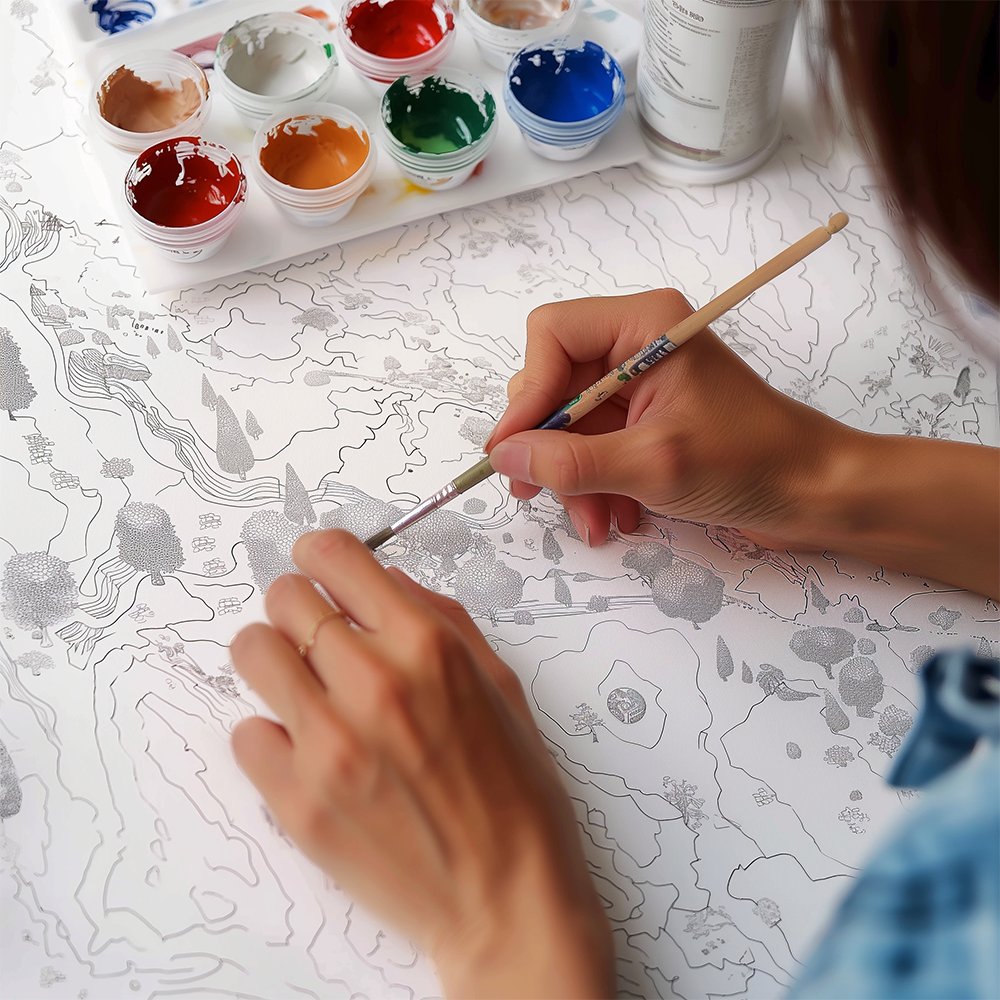 Person's hands painting a landscape outline with a brush and paints, close-up view.