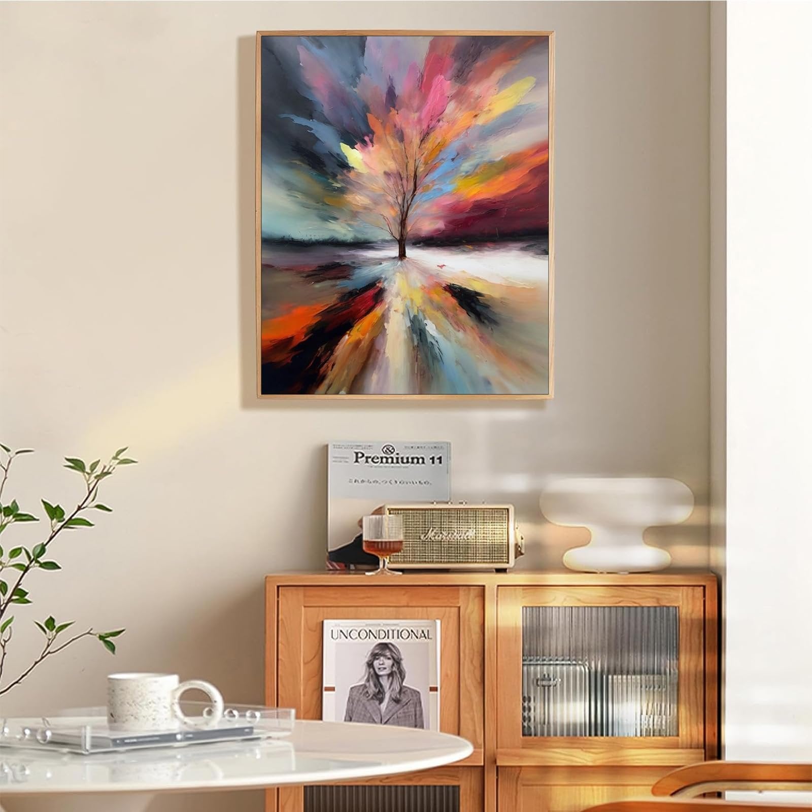 Abstract tree of life painting in a wooden frame hanging above a cabinet with books and a speaker