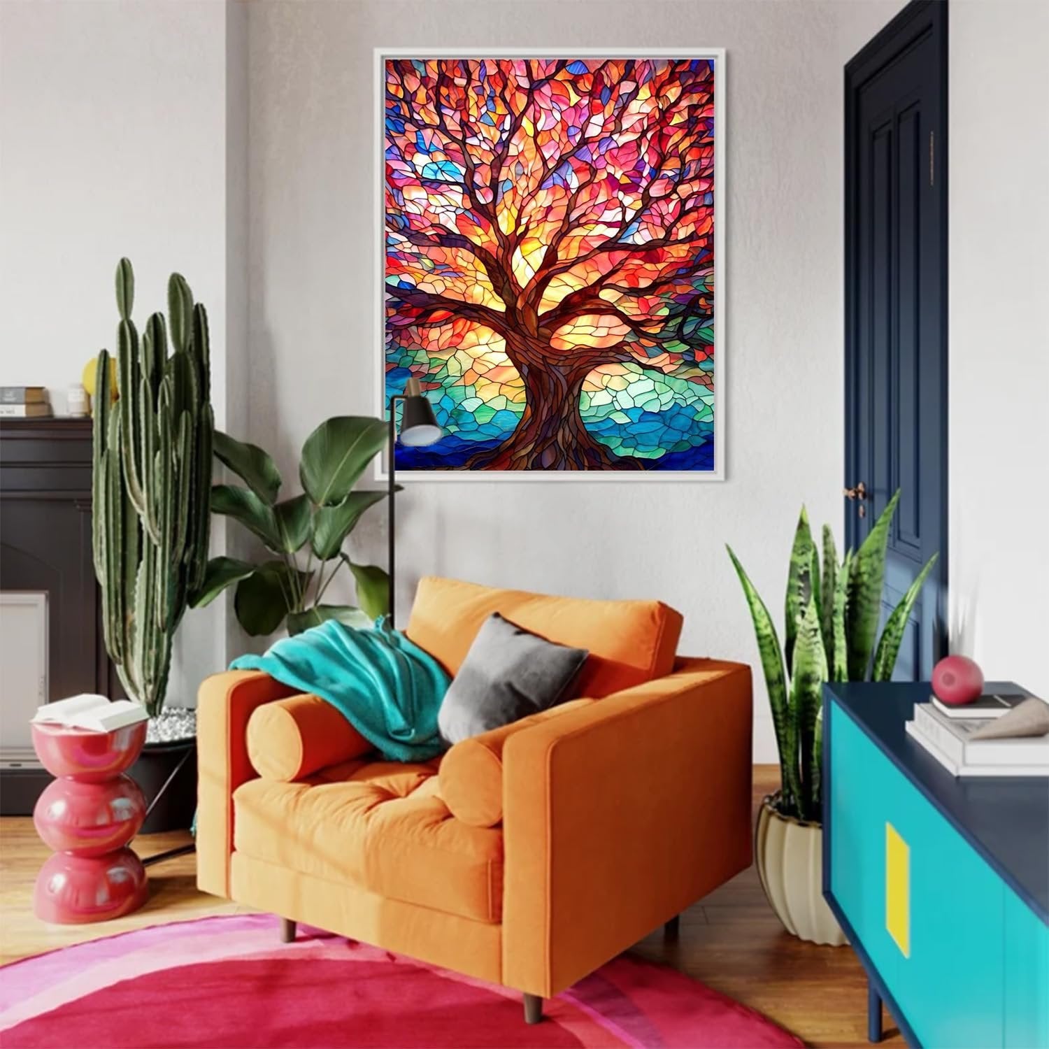 Framed stained glass style tree painting hanging on a wall in a living room with orange armchair and plants