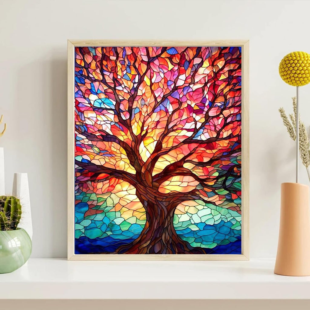Framed stained glass style painting of a tree with colorful leaves and a blue water base, displayed on a shelf with decorative items.