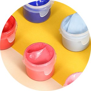 Close-up of small plastic containers filled with colorful acrylic paints, including pink, red, blue, and light blue.