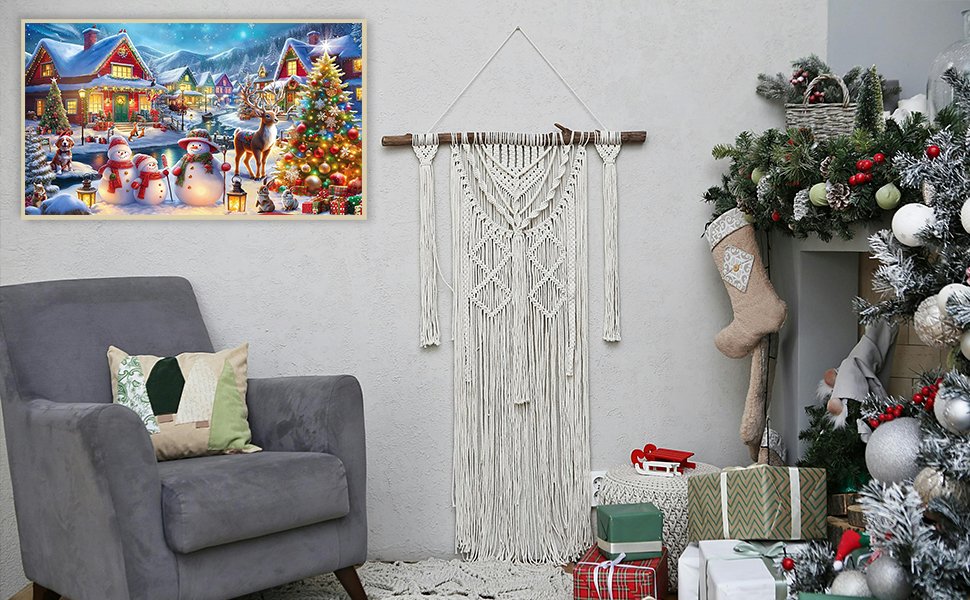 Christmas village scene diamond art kit displayed on a wall above a chair, next to a macrame wall hanging and a decorated Christmas tree.