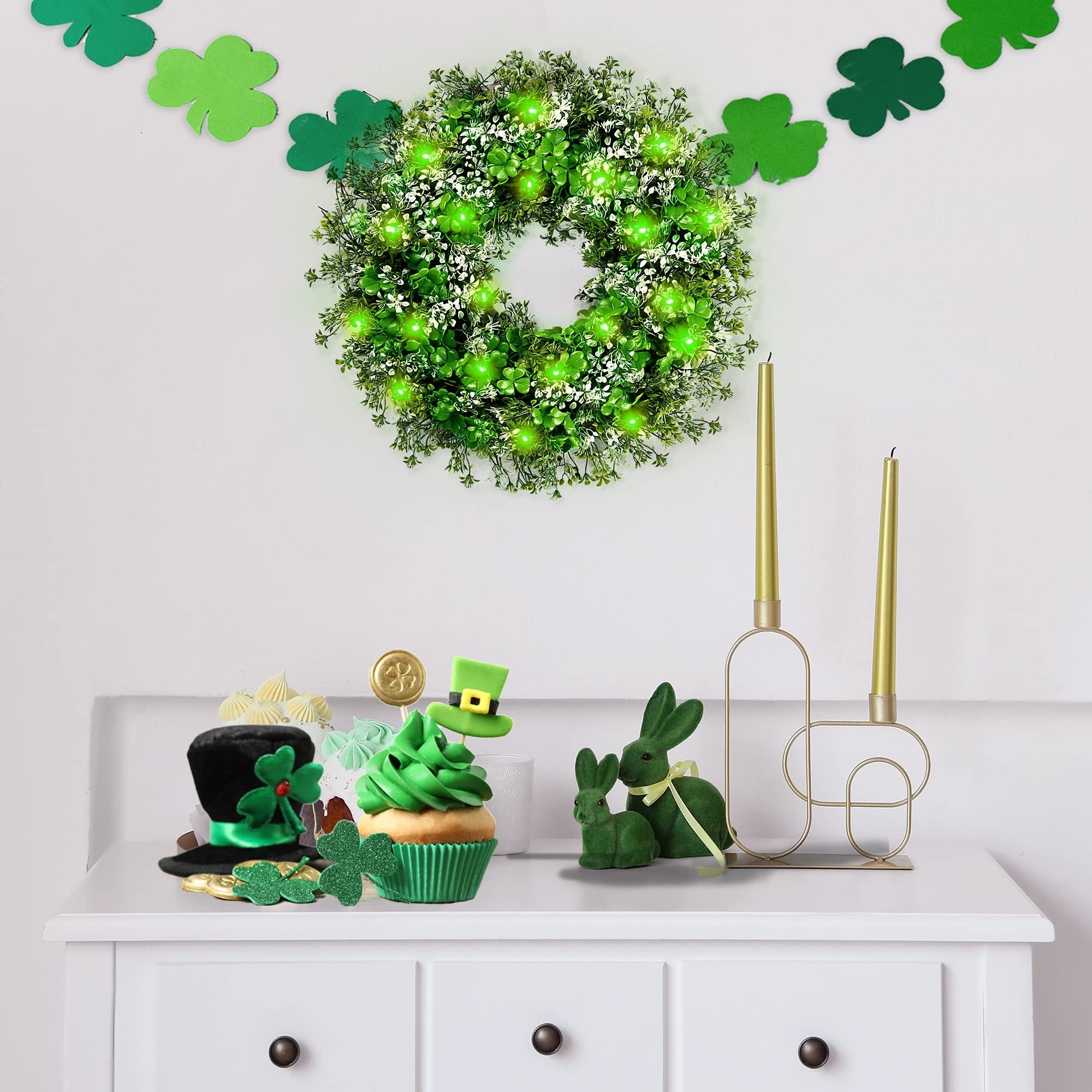 St. Patrick's Day themed display with a shamrock wreath, cupcake, and decorative bunnies on a white dresser.