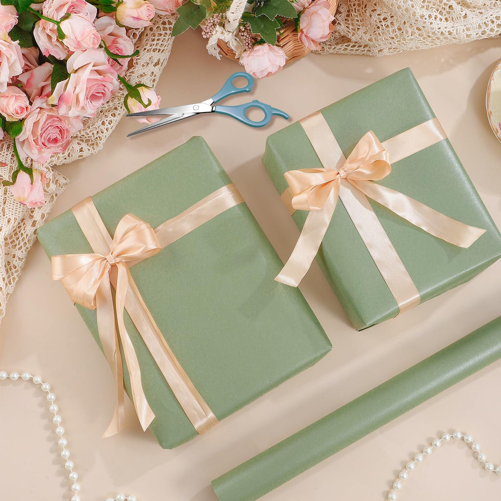 Two sage green gift-wrapped boxes with peach ribbon bows, scissors, and a roll of wrapping paper.