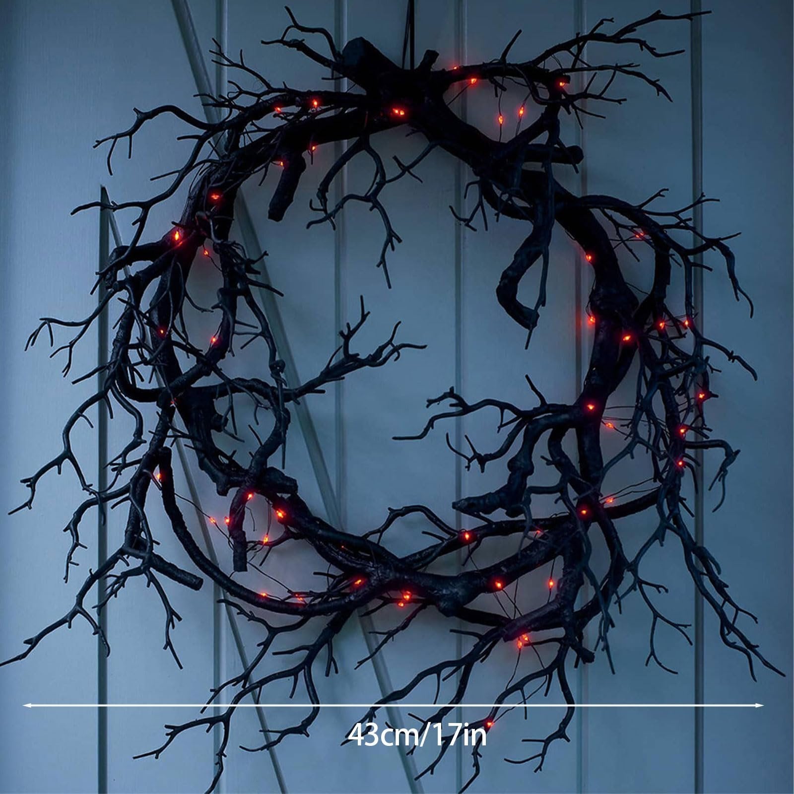 17 inch black twig Halloween wreath with red lights hanging on a white door