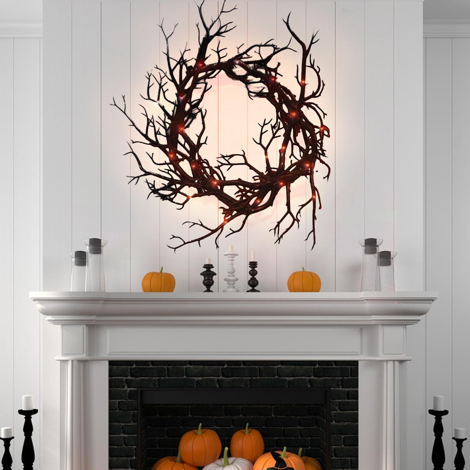 Black twig Halloween wreath with red lights hanging above a fireplace mantel decorated with pumpkins and candles.