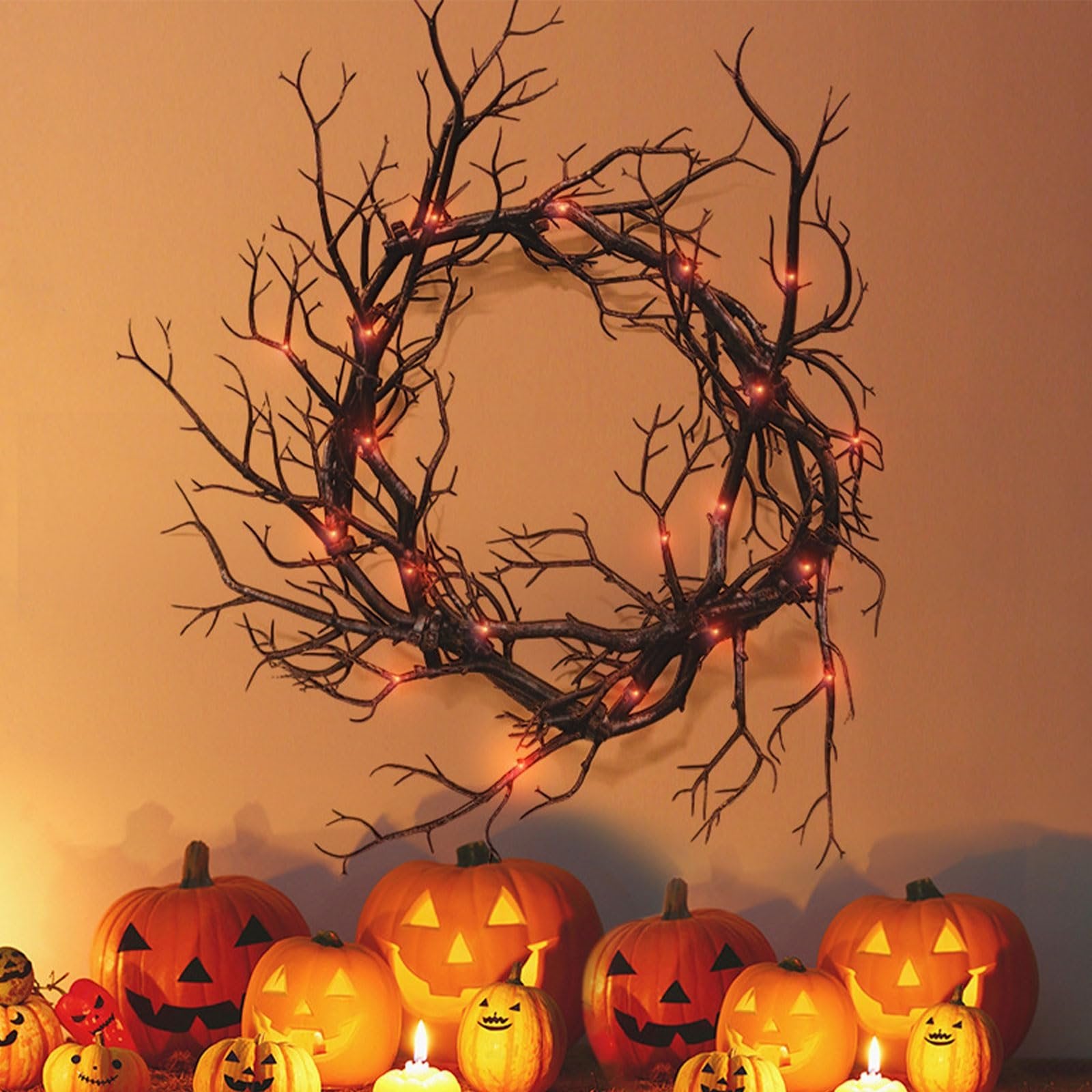 Black twig Halloween wreath with red lights, displayed above carved pumpkins and candles.