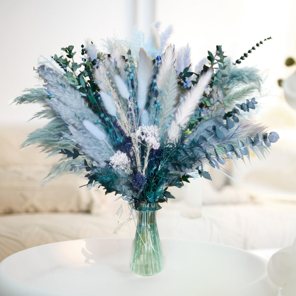 Dusty blue dried pampas grass bouquet with white grass, reeds, eucalyptus, bunny tail, and lavender in a green vase.