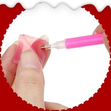 Close-up of hands using a pink diamond art pen to pick up a pink rhinestone for a keychain kit.