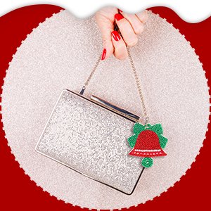 Woman's hand holding a silver glitter clutch purse with a red and green diamond art bell keychain attached.