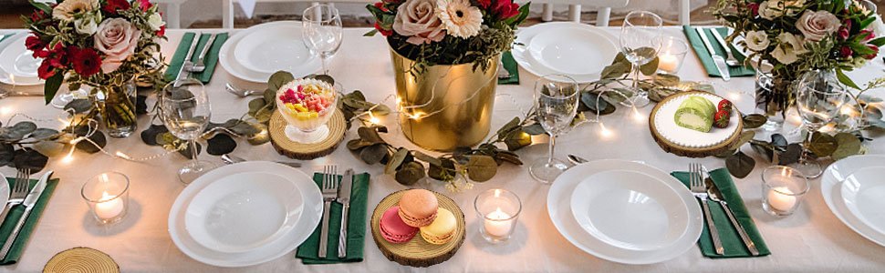 Table setting with floral arrangements, candles, and food items on wood slices.