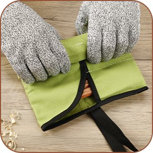 Hands wearing grey protective gloves folding a green storage bag with black trim