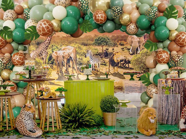 Jungle safari themed party setup with balloon arch, animal print balloons, palm leaves, and safari animal decorations.