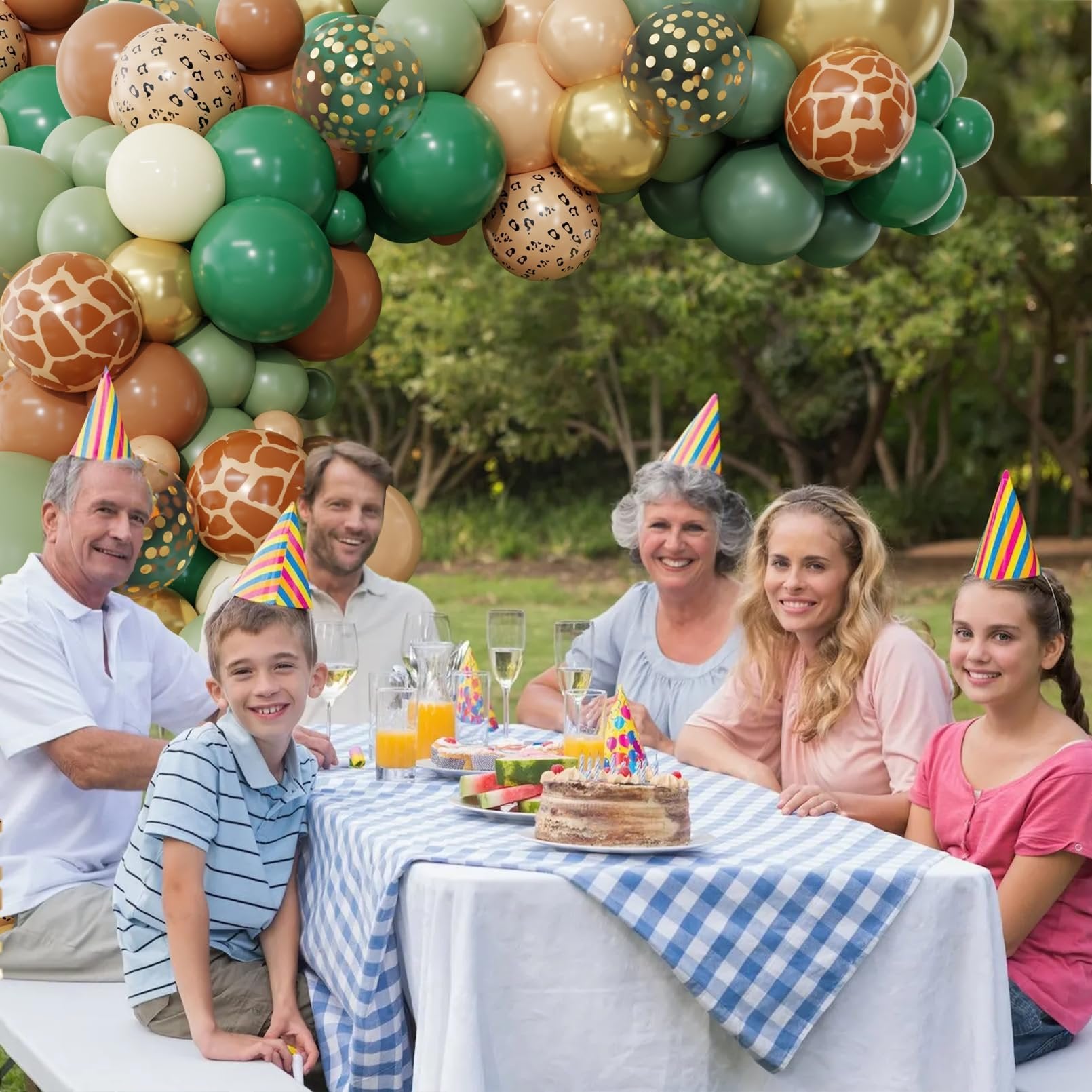 Family enjoying a picnic with a jungle safari balloon arch garland overhead and a cake on the table.