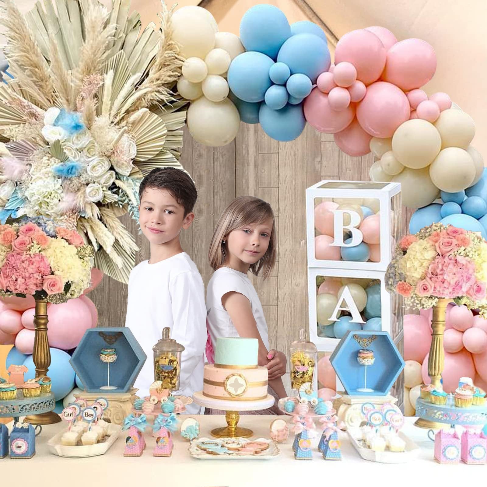 Gender reveal party table with pink and blue balloons, cake, cupcakes, and two children posing.