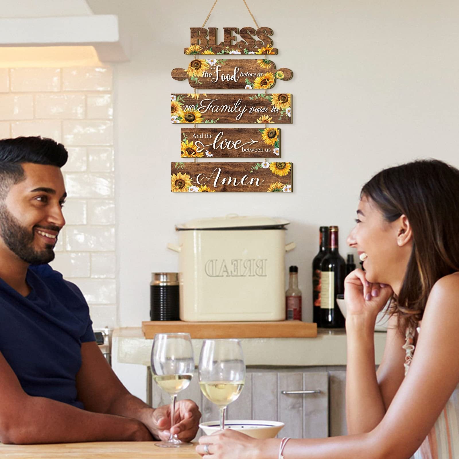 Wooden sunflower kitchen wall sign with rope, reading 'Bless the food before us, the family beside us, and the love between us. Amen.'