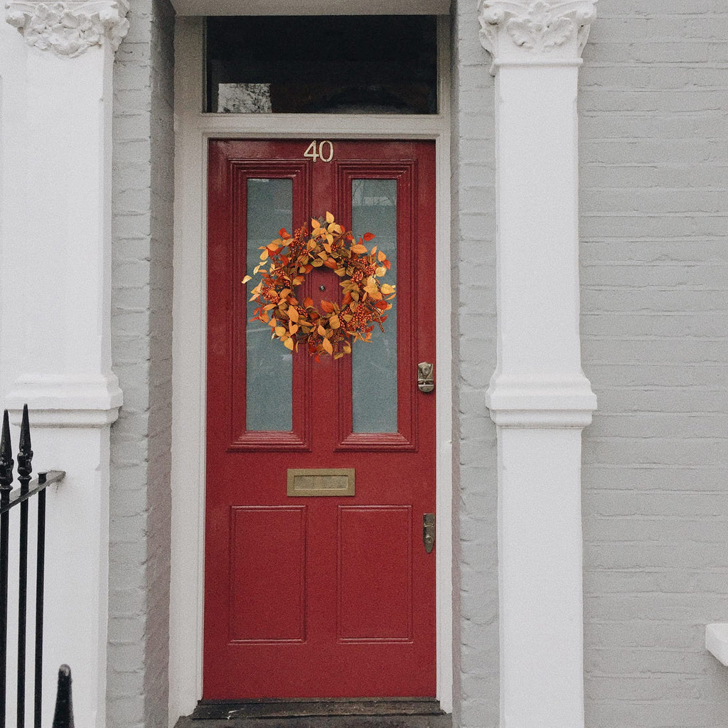 Autumnal wreath with eucalyptus leaves and berries hanging on a red front door with house number 40.
