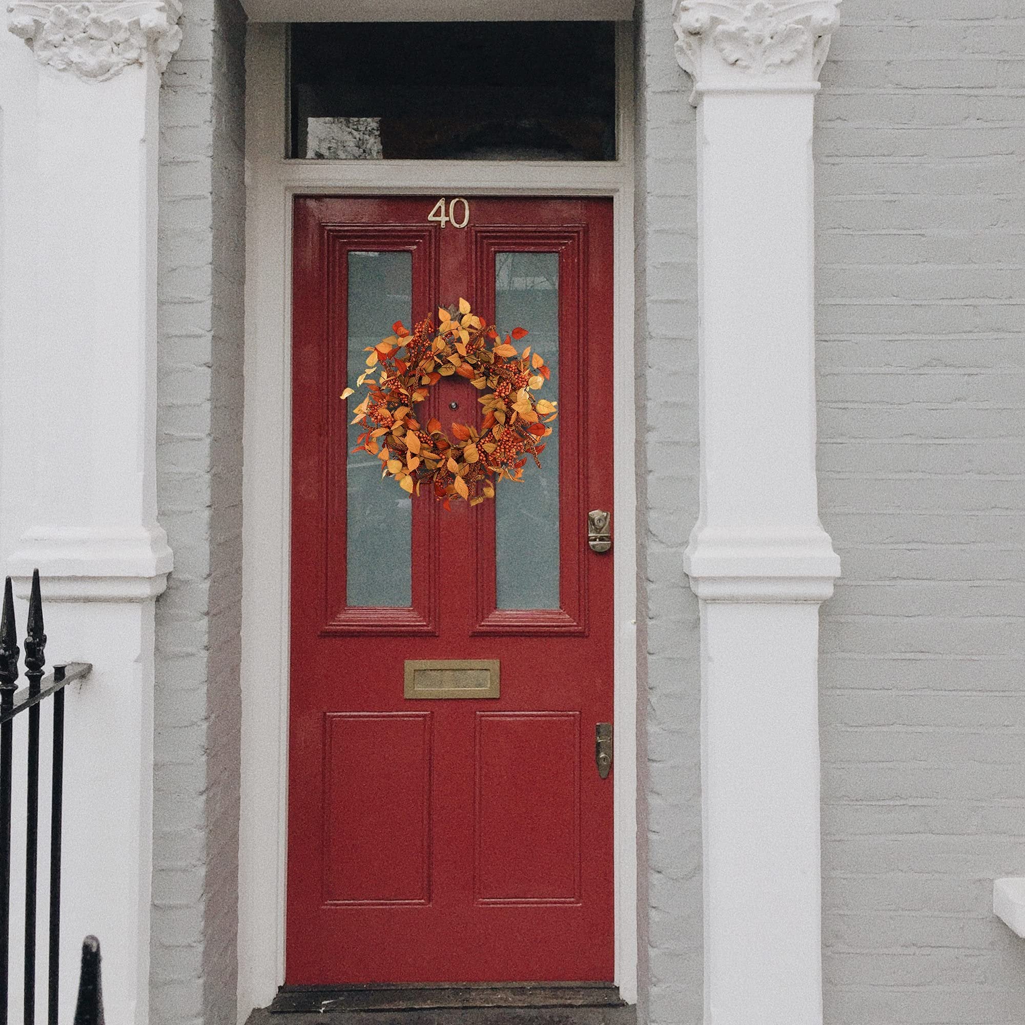 Autumnal wreath with eucalyptus leaves and berries hanging on a red front door with house number 40.