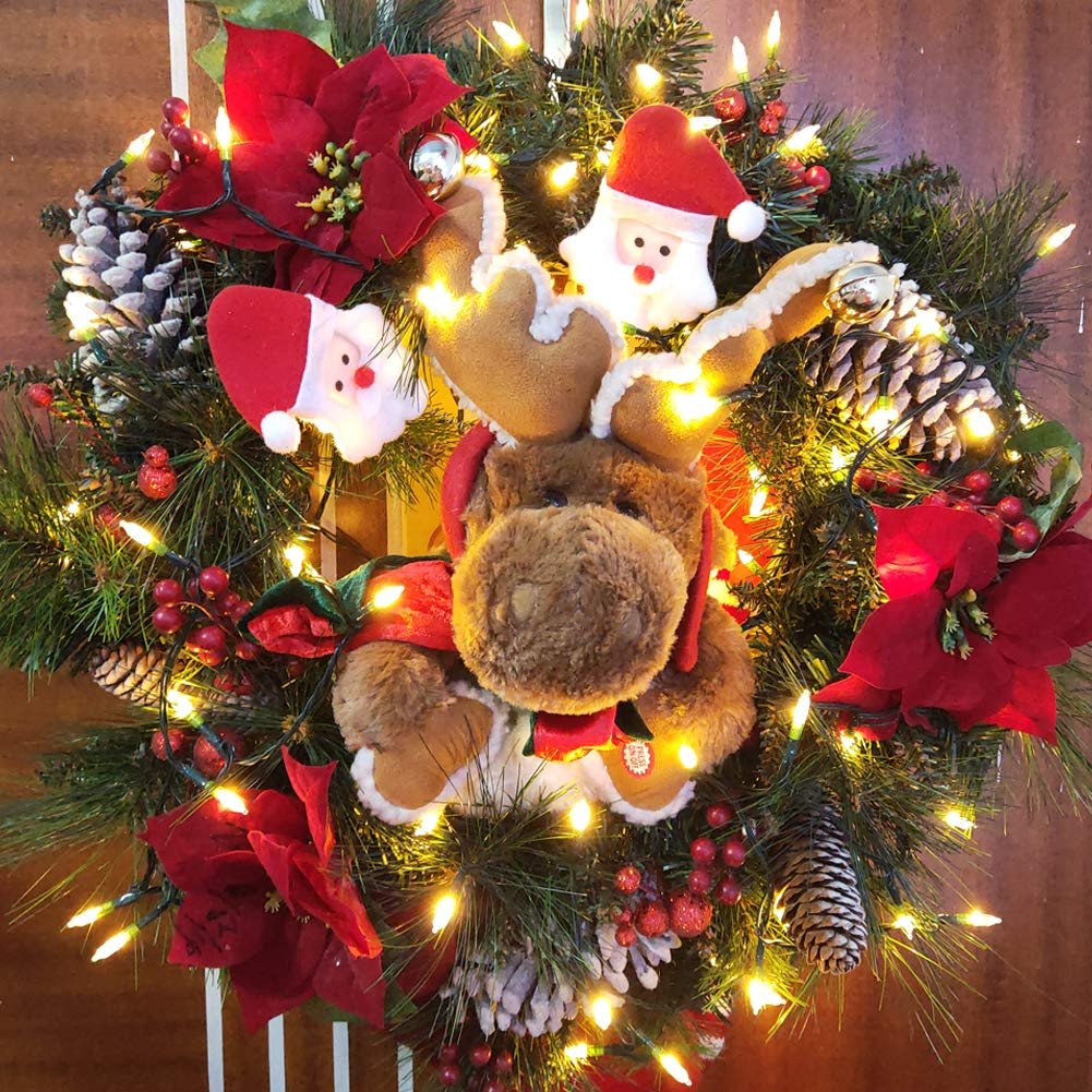 Christmas wreath with a plush reindeer, Santa Claus figures, poinsettias, pinecones, berries, and warm white LED string lights.