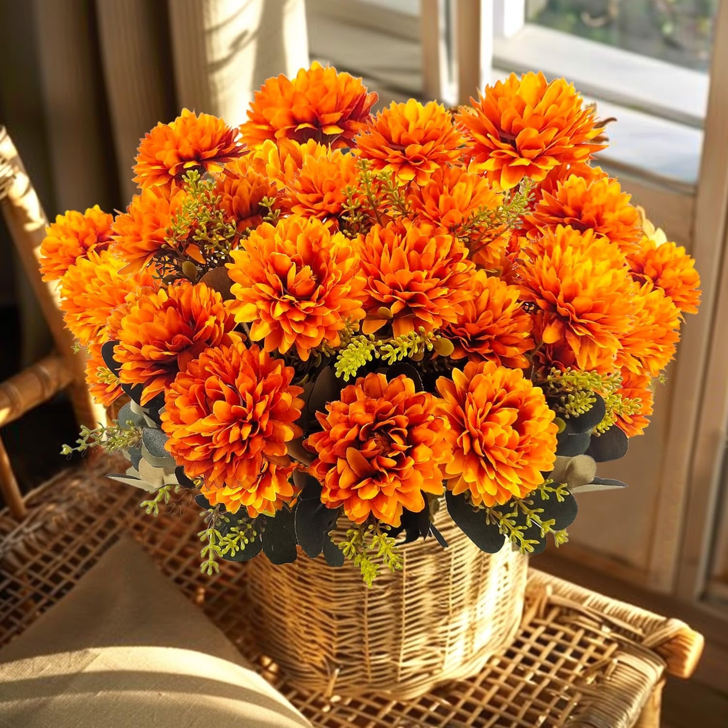 Artificial orange mum bouquet with wheat grass in a wicker basket on a chair