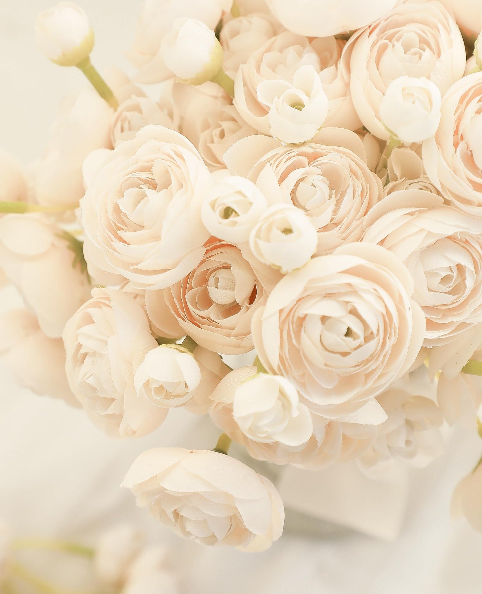 Champagne faux silk ranunculus flowers arranged in a bouquet, close-up view.