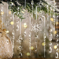 Assortment of clear acrylic Christmas ornaments including snowflakes, icicles, and beaded garlands hanging from a pine branch.