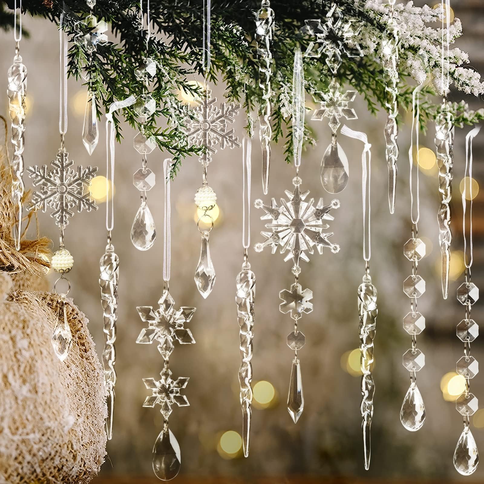 Assortment of clear acrylic Christmas ornaments including snowflakes, icicles, and beaded garlands hanging from a pine branch.