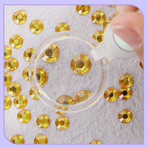Diamond painting light pen tip picking up a yellow rhinestone on a textured surface