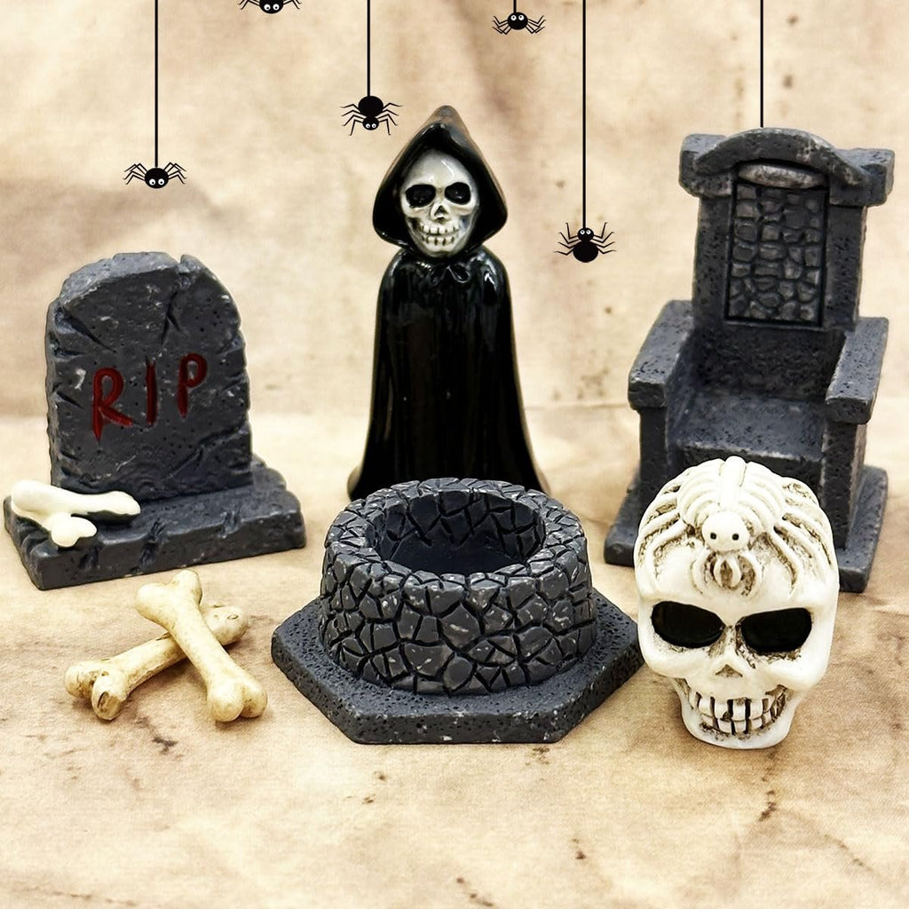 Halloween miniature figurines including a grim reaper, tombstone, skull, and well on a textured background with hanging spiders.