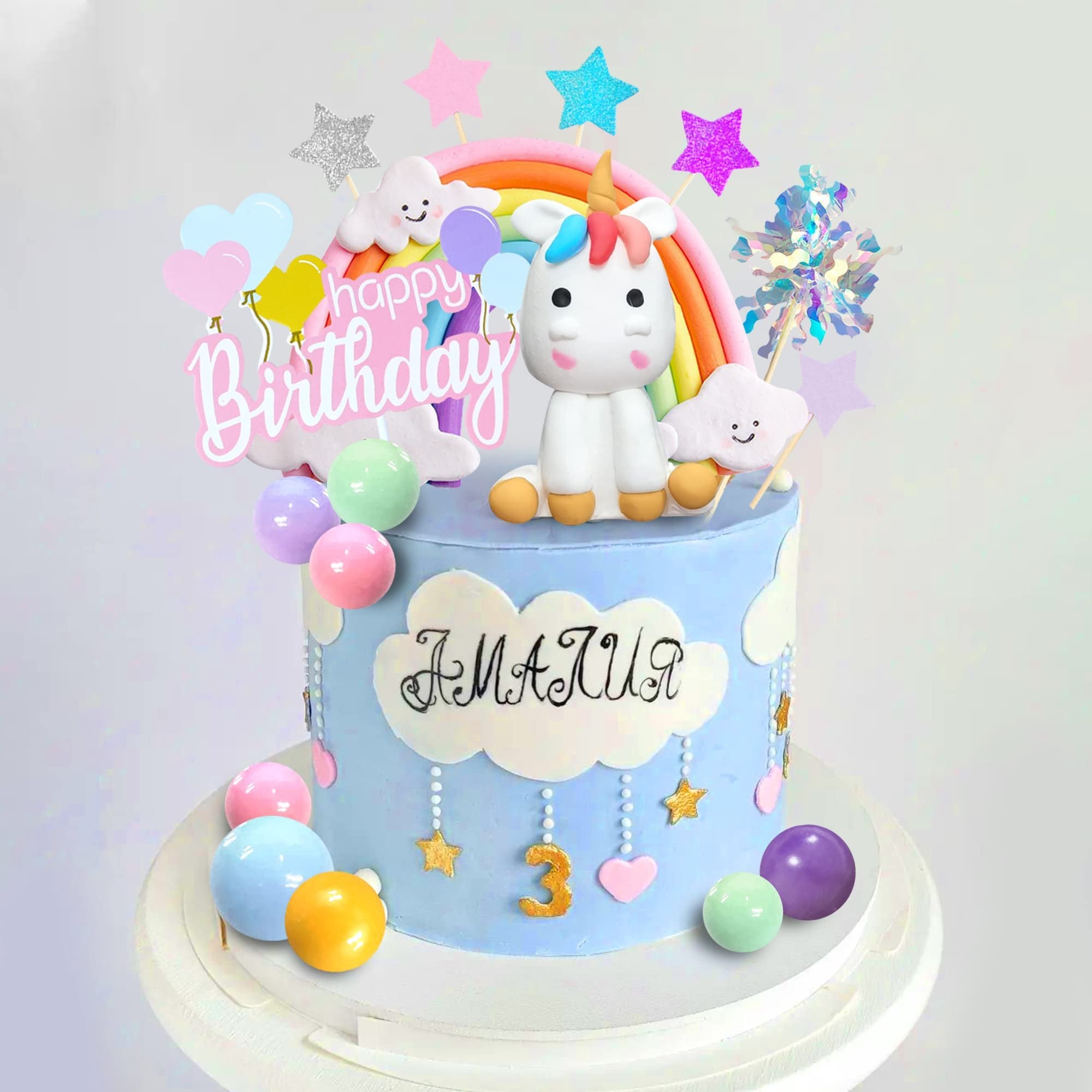 Unicorn rainbow cake topper set with 'Happy Birthday' text and decorative elements on a blue cake.