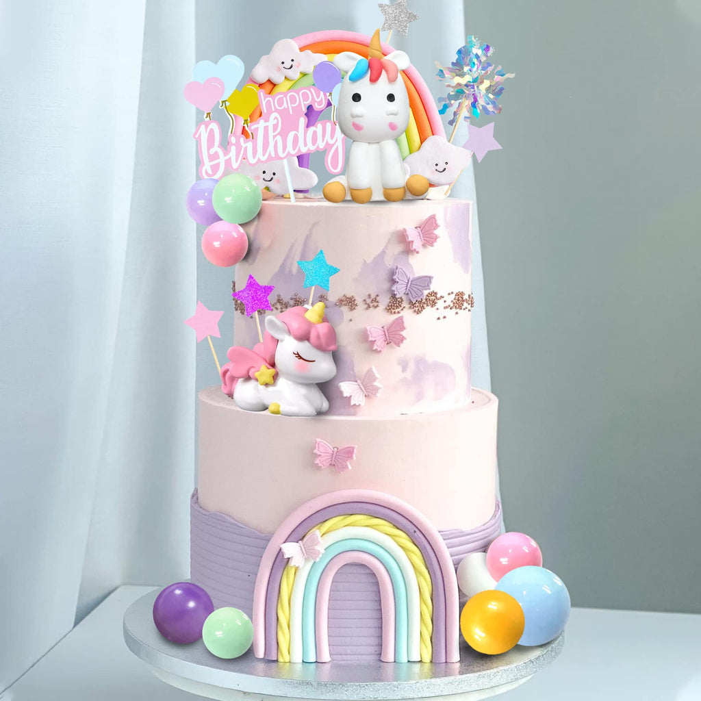 Unicorn rainbow cake topper set with happy birthday sign and colorful balloons on a tiered cake.