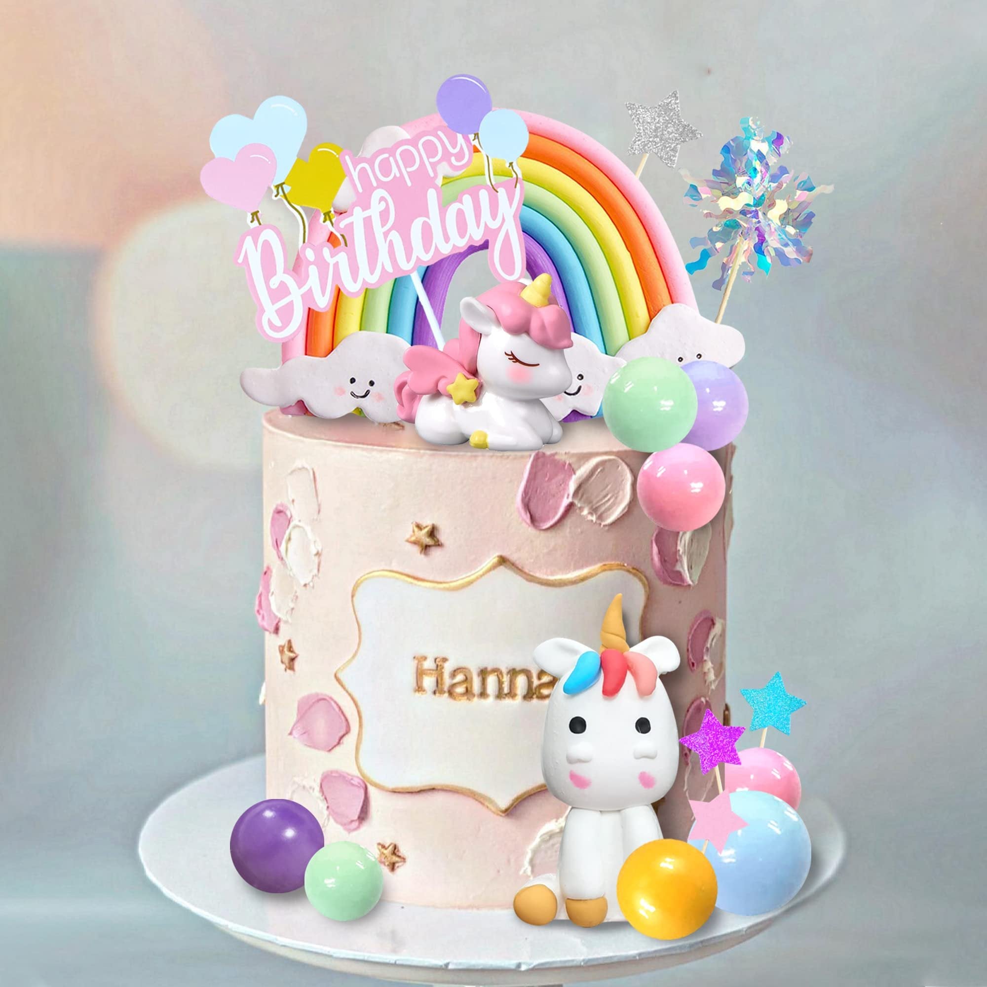 Unicorn rainbow birthday cake topper set with foam balls, foil firework, and paper stars on a decorated cake.