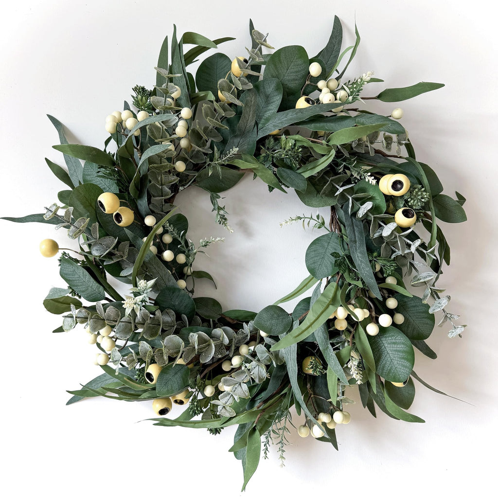 Artificial olive and eucalyptus wreath with white berries and yellow accents on a white background