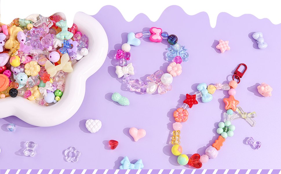 Assorted colorful acrylic beads in various shapes including flowers, bows, and hearts, arranged on a purple background with two finished bracelets.