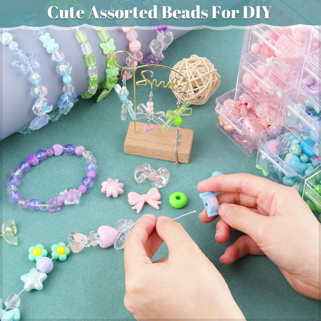 Hands stringing assorted colorful acrylic beads into bracelets and jewelry, with bead containers and finished bracelets visible.