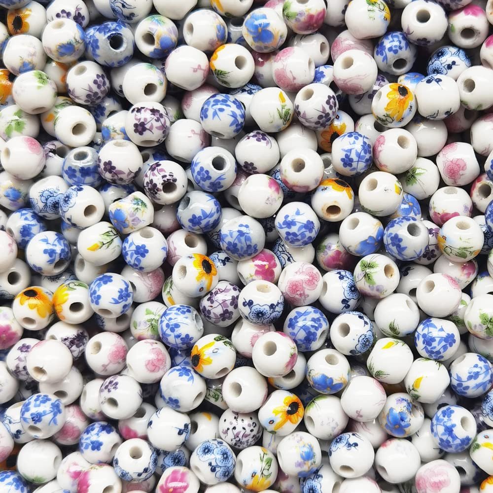 Pile of 8mm round porcelain beads with floral patterns in blue, pink, and yellow on white.