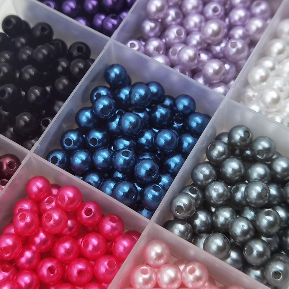 Close-up of a multi-compartment organizer filled with colorful plastic pearl spacer beads in various shades.