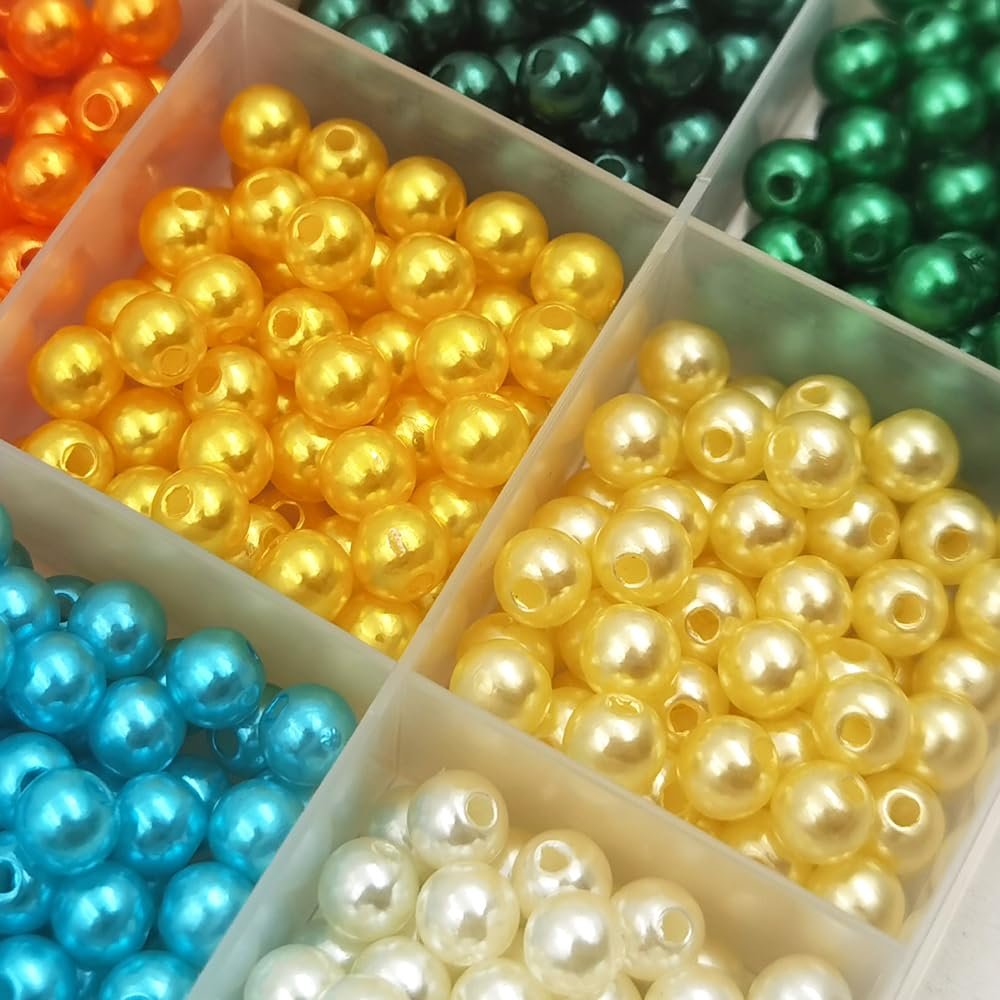 Close-up of assorted colorful plastic pearl spacer beads in a divided storage box, showing yellow, white, blue, orange, and green beads.