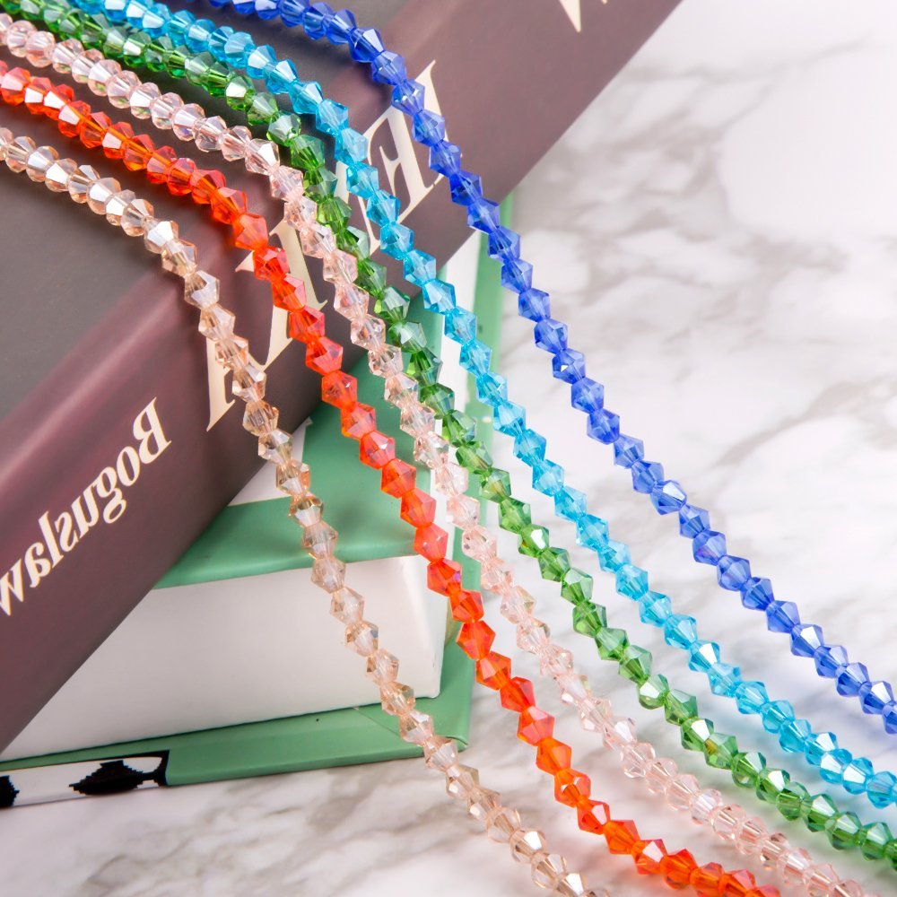Strands of 4mm faceted crystal bicone beads in various colors draped over books.
