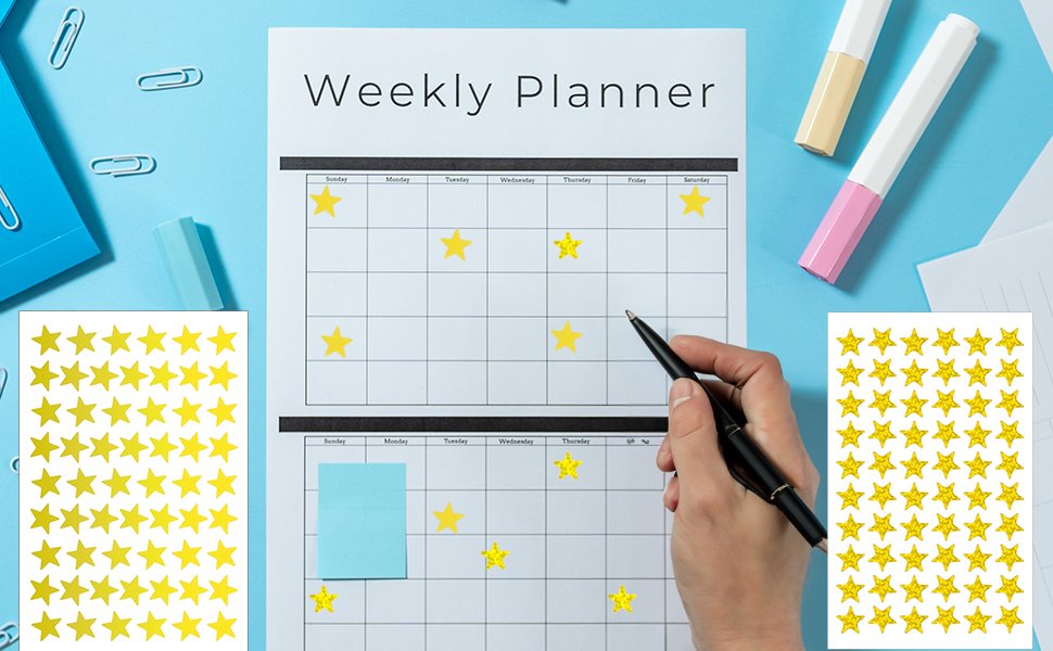 Holographic gold star stickers being placed on a weekly planner by a hand holding a pen.
