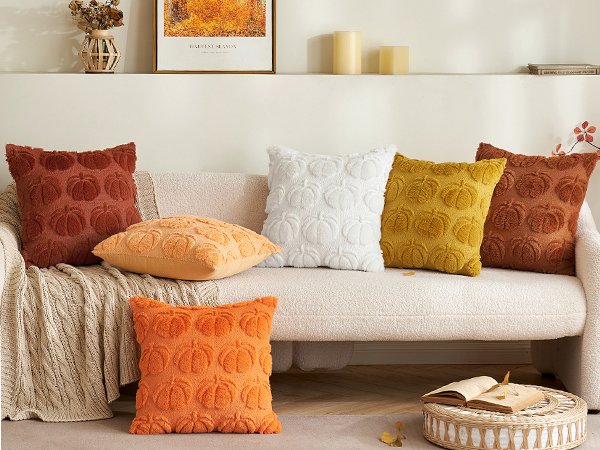 Set of five textured throw pillow covers with pumpkin designs arranged on a sofa, in rust, orange, white, and yellow colors.