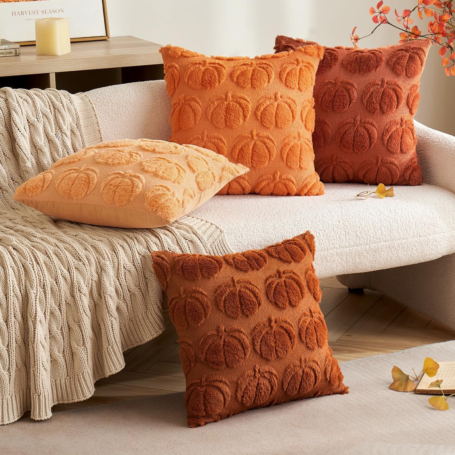 Four textured throw pillow covers with embossed pumpkins arranged on a sofa and floor.