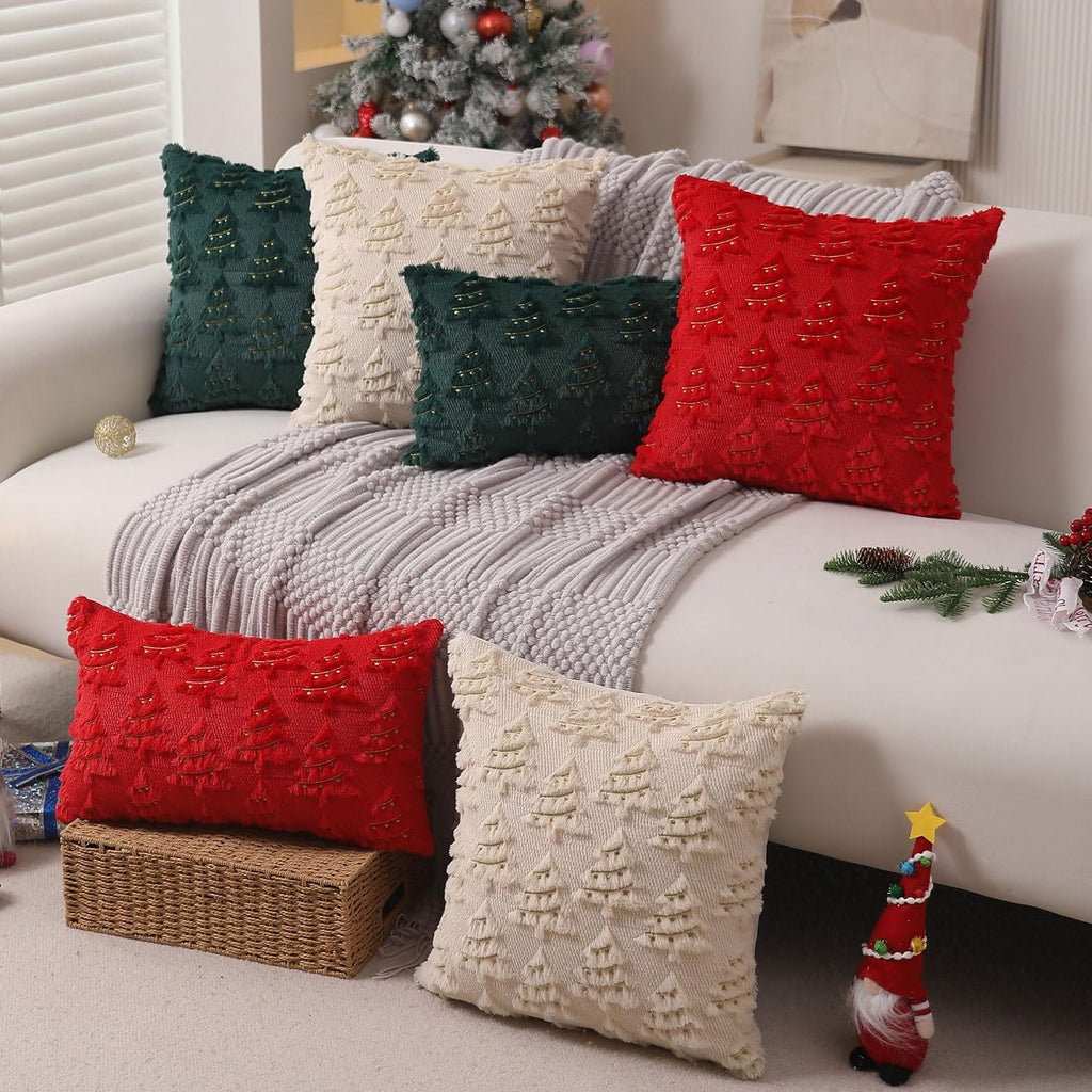 Set of Christmas pillow covers in red, green, and beige with embroidered trees and gold beads, arranged on a sofa with a Christmas tree in the background.