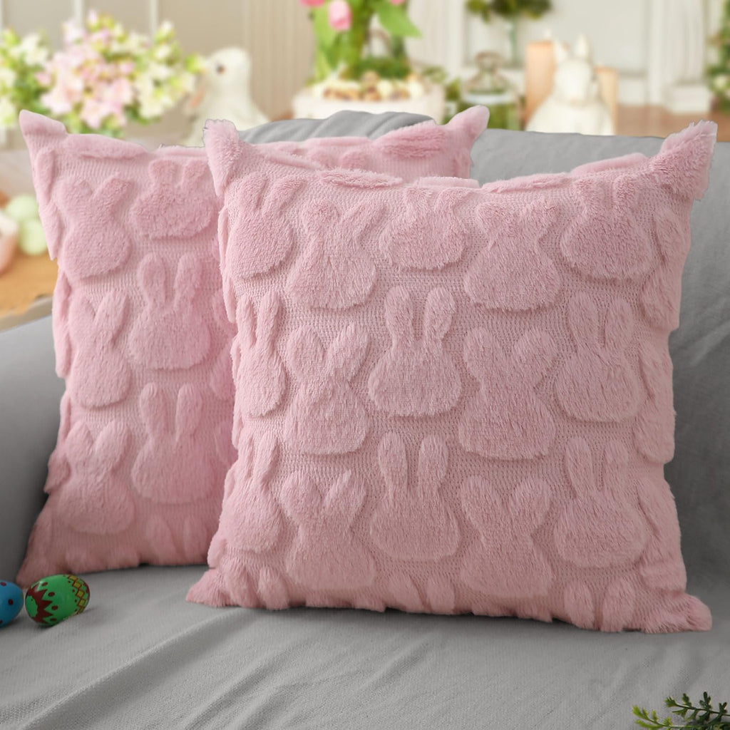 Two pink plush faux fur Easter bunny throw pillow covers on a gray couch with decorative eggs.