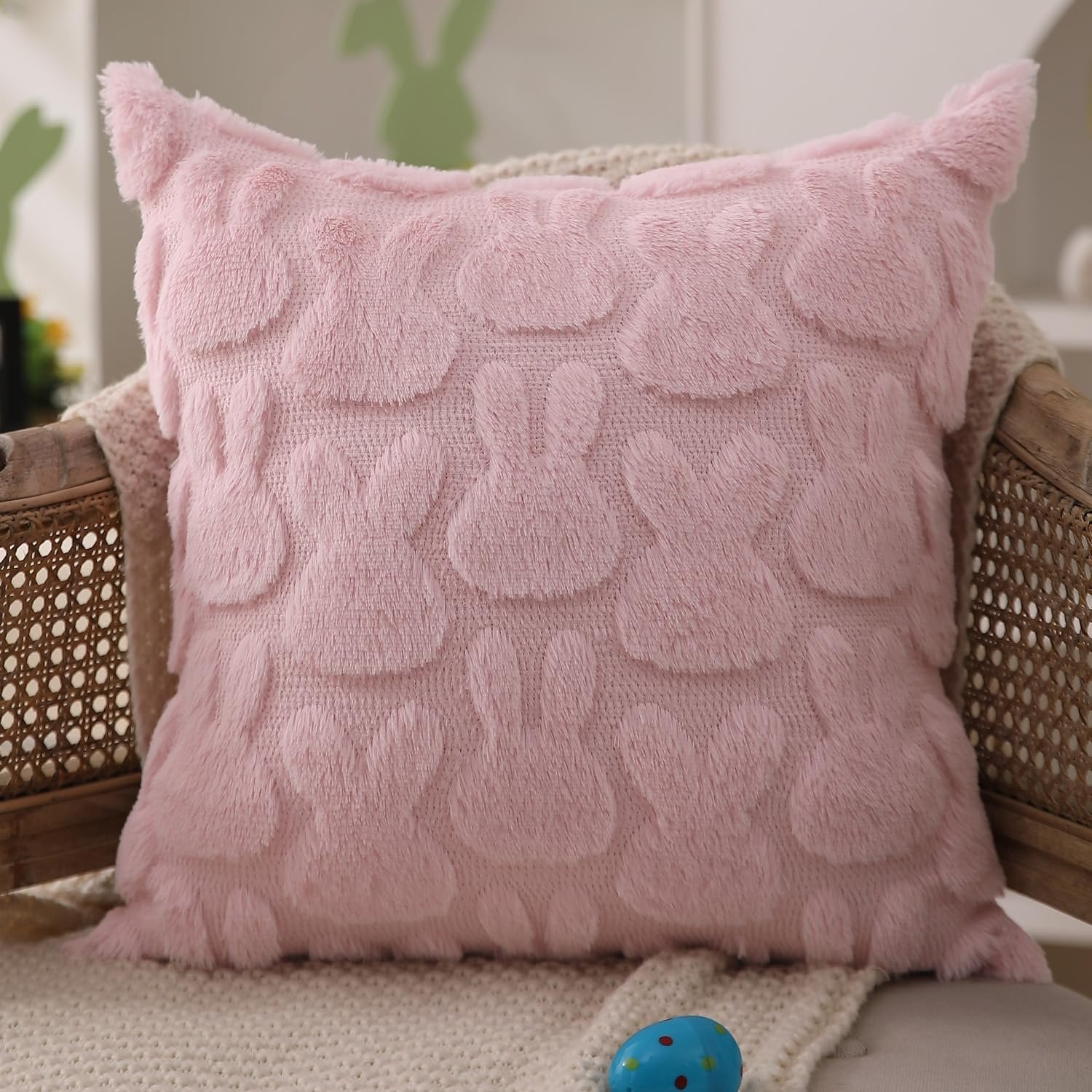 Pink plush faux fur Easter rabbit throw pillow cover on a chair with a blanket and an egg.