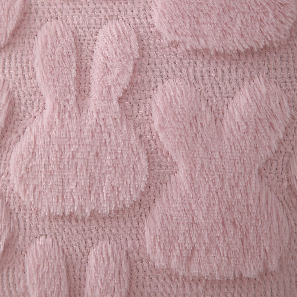 Close-up of pink plush faux fur pillow cover with jacquard bunny pattern and textured weave.